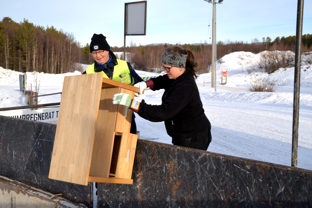 Två personer kastar avfall på återvinningscentralen.