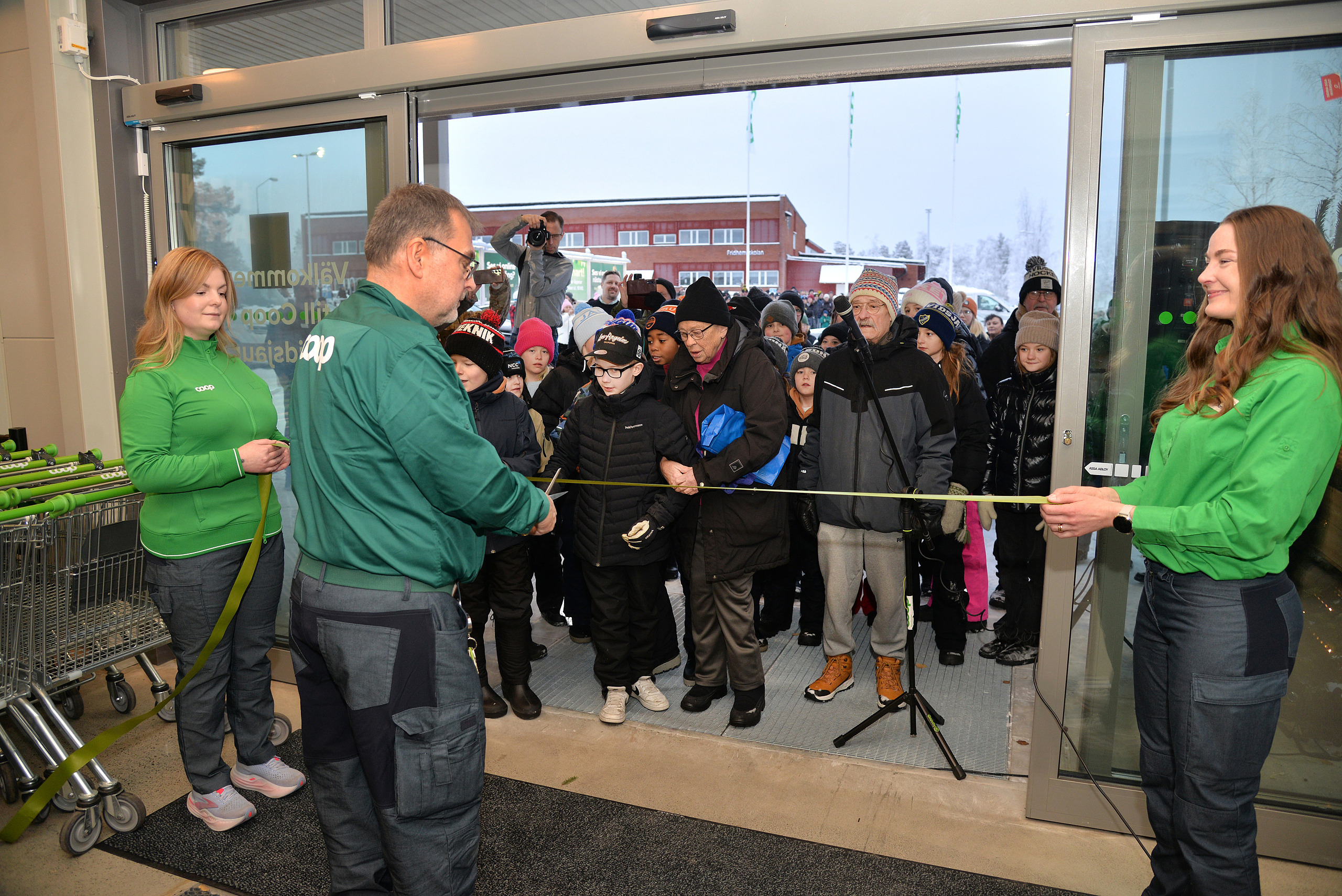 Coops butikchef Ulf Isaksson, klippper invigningsbandet, och hälsar den långa kön välkommen in i nya butiken.