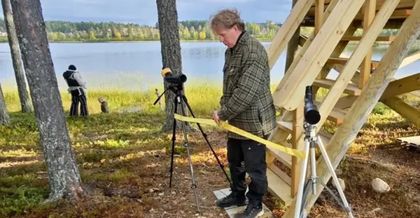 En man klipper ett band framför ett torn.
